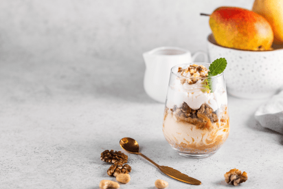 Birnen-Haselnuss-Dessert mit Karamell im Glas mit CremiG Vanille auf einem Tisch mit Birnen und Nüssen